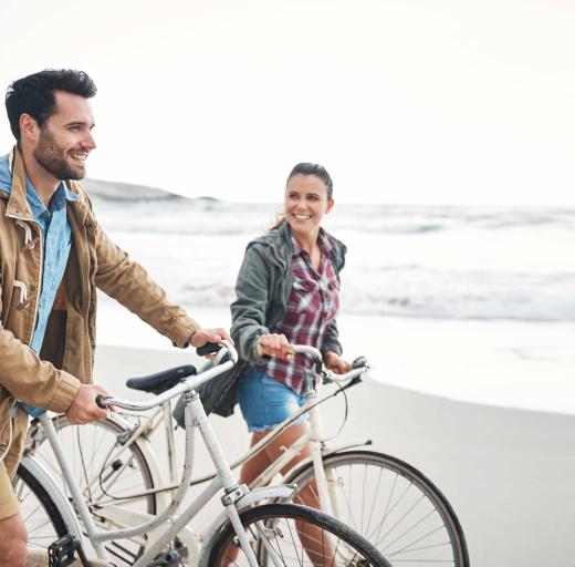 Stel lopend op het strand, fiets aan de hand